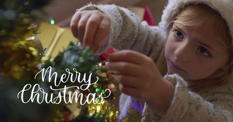 Joyful Child Decorating Christmas Tree with Merry Christmas Text Overlay