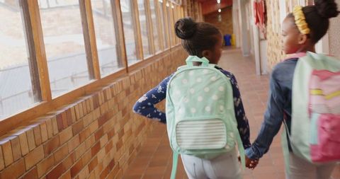 Two Schoolgirls Holding Hands in School Corridor