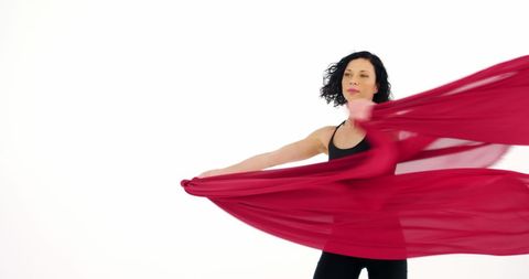 Graceful woman dancing with flowing red fabric