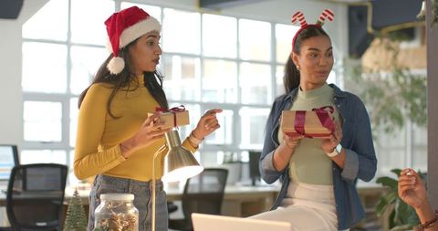 Diverse coworkers exchanging holiday gifts in modern office celebrating festive teamwork