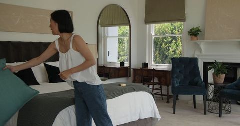 Woman Making Bed in Bright and Cozy Bedroom