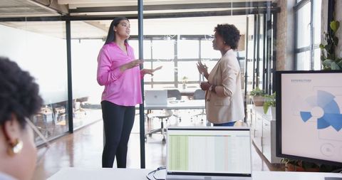 Diverse female colleagues engaging in professional discussion in modern office