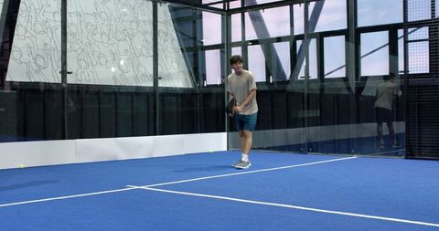 Man Playing Padel Inside Modern Glass Court