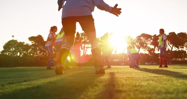 This photo captures youth soccer players training on a field during sunset. Ideal for illustrating youth sports and activities, team spirit, outdoor exercise, and active lifestyle promotions. It can be used for websites, blogs, advertisements, and sports-related content.