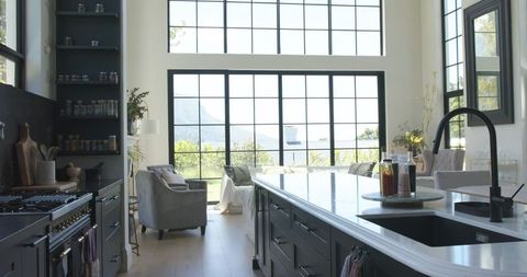 Modern open-plan kitchen with marble island, black faucet and panoramic grid windows