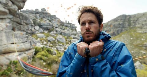 Man bracing against cold in blue jacket in mountain landscape