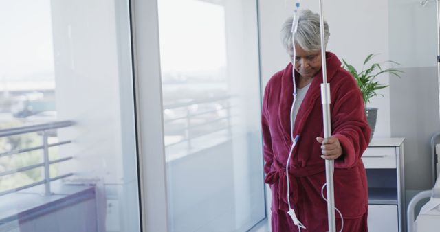 Elderly Woman in Hospital Gown Holding IV Pole in Hospital Room - Download Free Stock Images Pikwizard.com