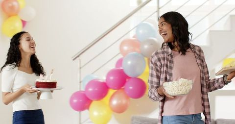 Joyful Women Preparing for Home Celebration with Cake and Snacks
