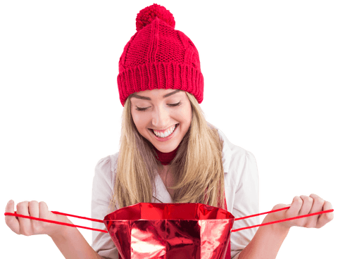 Smiling blonde opening red gift bag in cozy winter hat