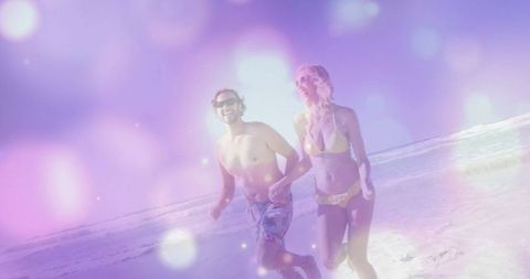 Smiling Couple Holding Hands Upon Romantic Beach Stroll
