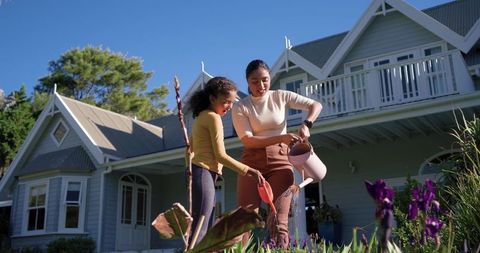 Mother and daughter gardening together in sunny suburban front yard
