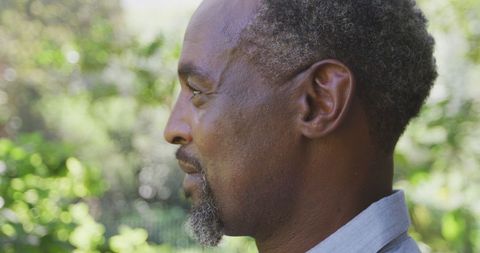 Thoughtful Senior Man Smiling in Lush Garden