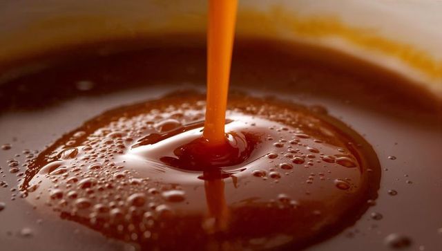 Pouring Glossy Caramel Syrup Forming Amber Pool with Bubbles Macro Closeup Texture