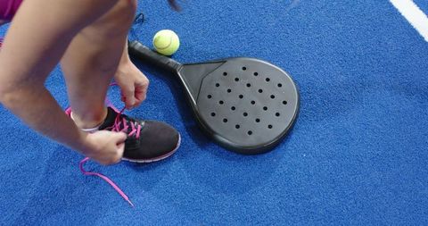 Woman preparing for paddle tennis on blue sports court