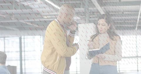 Colleagues discussing project in bright open office - woman holding folder, man on phone