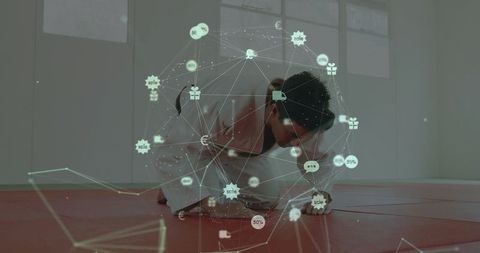 Martial artist crouching on red mat with holographic data network for ar training