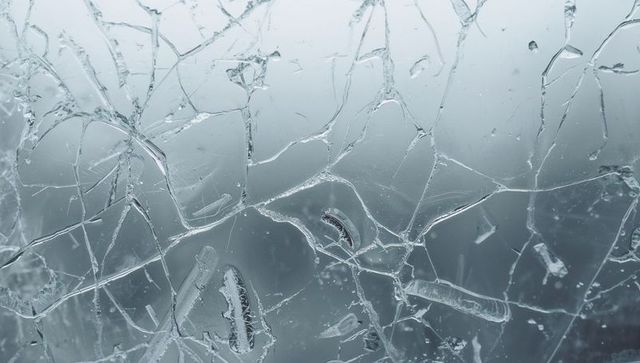 Shattered frosted windshield glass revealing ice crystals and droplets macro texture