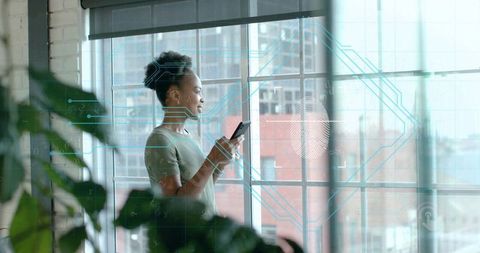 Woman Using Smartphone by Urban Window with Futuristic Digital Overlay
