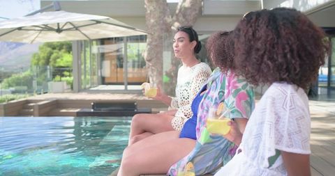 African American Women Relaxing by Pool with Lemon Drinks at Luxury Resort Terrace
