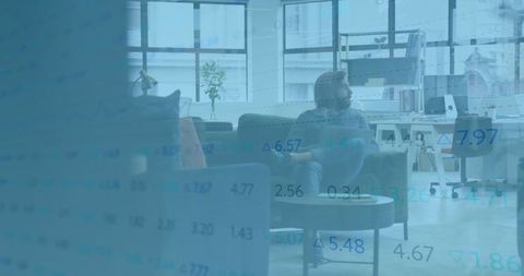 Young professional sitting in modern office lounge analyzing financial data overlay