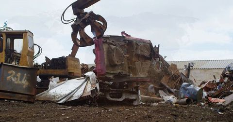 Industrial machinery operating in muddy auto salvage yard