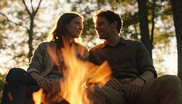 Couple sharing intimate campfire moment during golden hour in forest