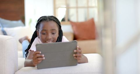 African american girl relaxing on couch using tablet for learning and entertainment