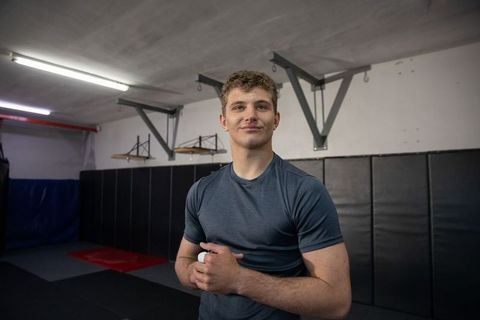 Young male fighter preparing with taped hands in martial arts gym, focused training portrait