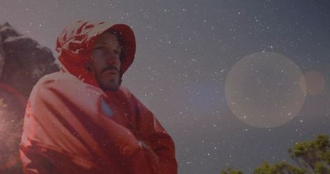 Man in Red Parka Exploring at Rocky Ridge Under Starry Sky