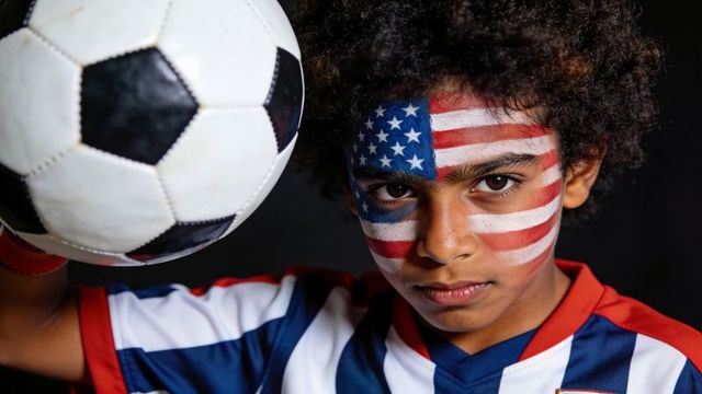 Determined youth soccer player with american flag face paint holding ball