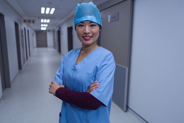 Side view of female surgeon with arm crossed standing in corridor at hospital