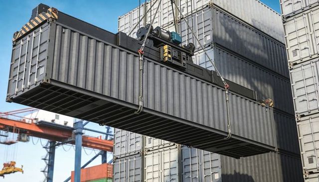Heavy lift gantry crane hoisting dark gray intermodal container over port container yard