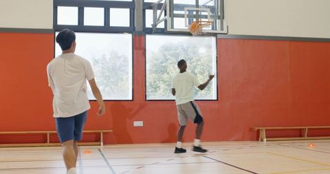 Youth basketball training drill african american player dunking during indoor practice