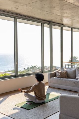 Meditating in coastal living room with ocean view and glass balcony