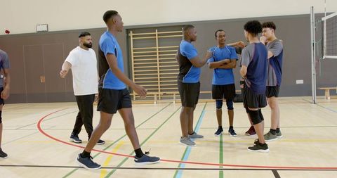 Young diverse male volleyball team discussing strategy and planning tactics in indoor gym