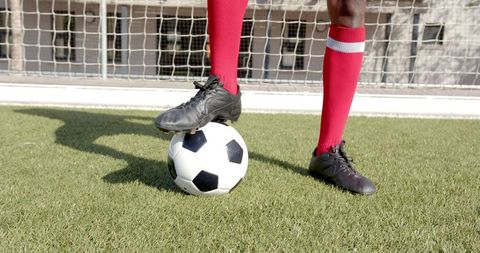 Close-up of soccer player controlling ball on turf near goal