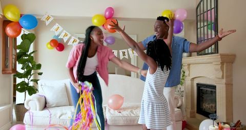 Joyful family celebrating birthday with dancing and confetti
