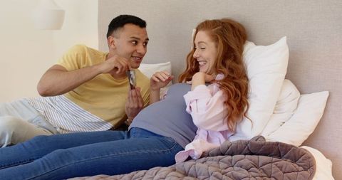 Expectant couple sharing joyful pregnancy ultrasound moment on bed