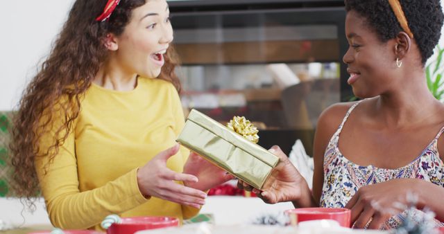 Happy diverse female friends opening christmas presents. Spending quality time at home together at christmas.