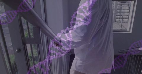 Mature man standing on stair landing gripping metal railing with purple dna helix overlay