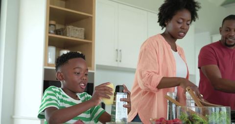 African american family preparing meal together in bright kitchen, child grating cheese