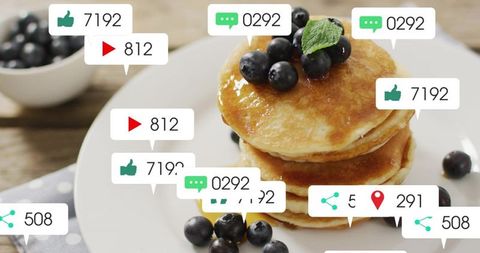 Stacking syrup-glazed pancakes topping with blueberries and mint, showing social media icons