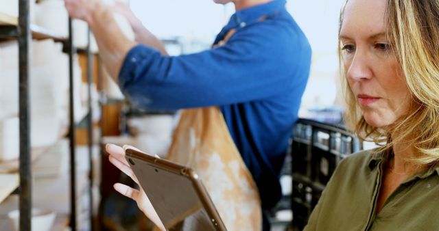 Businesswoman Using Tablet in Workshop with Worker in Background - Download Free Stock Images Pikwizard.com