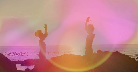 Couple Stretching on Ocean Rocks at Vibrant Sunset