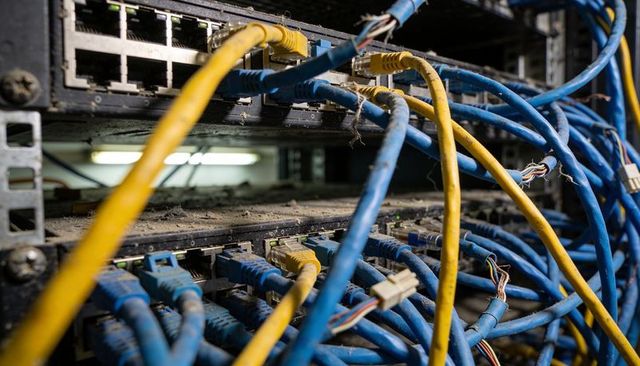 Frayed ethernet cables plugging into dusty patch panels in server rack