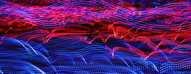 Abstract light patterns in blue and red form wavy lines, creating a vibrant and dynamic visual effect. Perfect for use in technological presentations, creative projects, backgrounds for websites and advertisements, and any artistic compositions that require a sense of motion and energy.