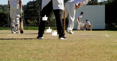 Batsman Facing Bowler on Sunny Cricket Field with Spectator Watching