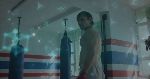 Shirtless boxer training near heavy bags with futuristic holographic overlay
