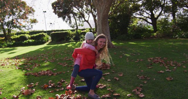 Young woman giving piggyback ride to laughing little girl in autumn park - Download Free Stock Images Pikwizard.com