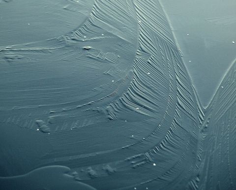 Frost patterns showing on window glass close-up blue ice texture winter background